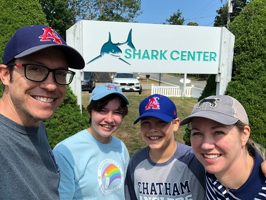 A happy family in front of the sign for AWSC Shark Center in Chatham.
